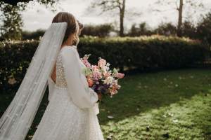 Bride with veil in ther hair walks throughout the green gardens of Hunter Valley wedding venue Wallalong House