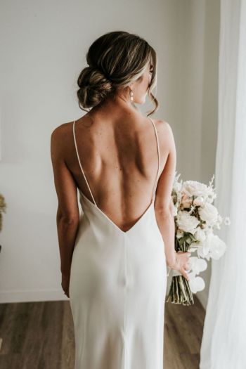 Bride holding flowers looking out of the window before her ceremony at Hunter Valley wedding venue The Woodhouse Wollombi