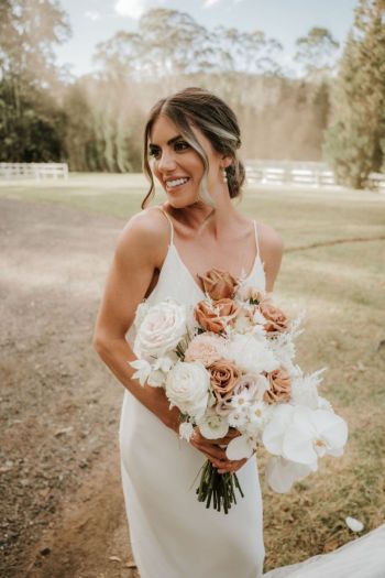 Bride holding flowers and smiling at Hunter Valley wedding venue The Woodhouse Wollombi