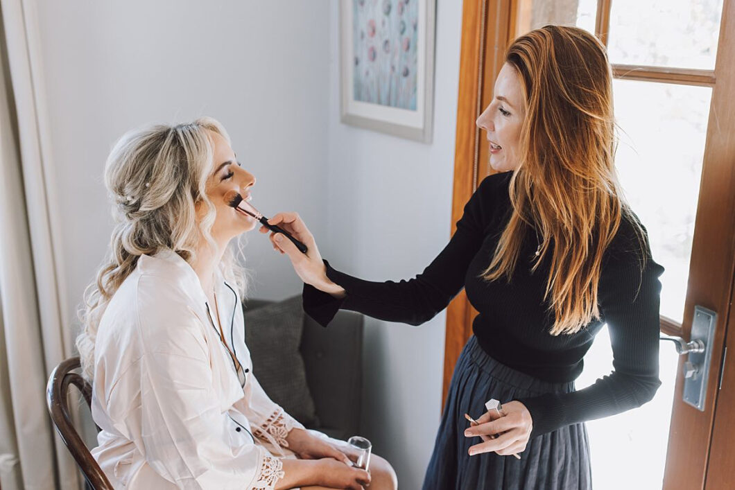 Bride sitting in chair having her makeup done by the best Hunter Valley makeup artist on her wedding day